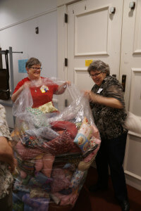 Yes - this is a picture of our April meeting devolving into a pillow fight!!  Really, all in fun as Guild President - Millie and Charity Bee Chair make a feeble effort to bag the nights successful stuffing of pillows supporting cancer victims.